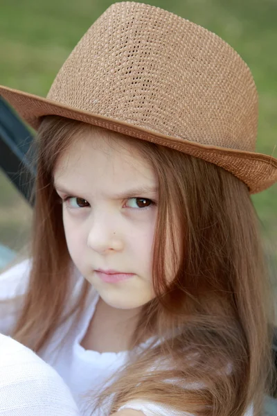 Porträt eines kleinen Mädchens in einem weißen Kleid in einem Sommerpark sitzt auf der Bank in der Straße — Stockfoto