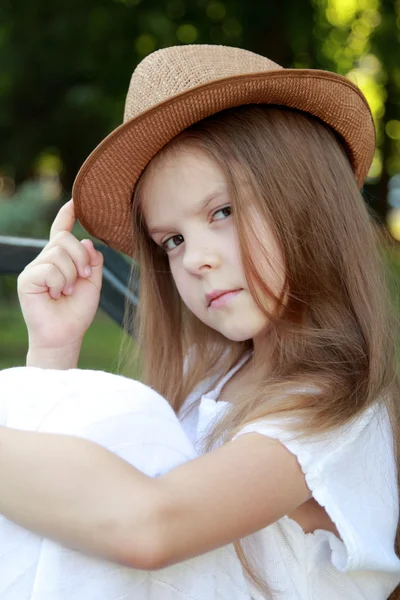 Adorabile bambina con un cappello in posa presso la fotocamera nel parco estivo all'aperto — Foto Stock