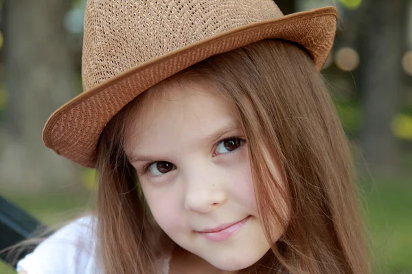 Schöne kleine Mädchen in einem weißen Kleid und Hut im Freien — Stockfoto