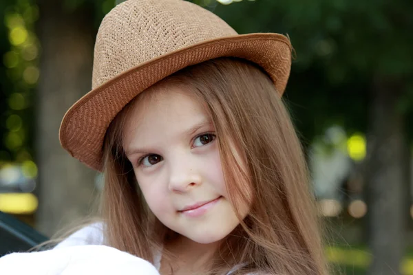 Entzückendes kleines Mädchen mit Hut posiert im Sommerpark im Freien vor der Kamera — Stockfoto