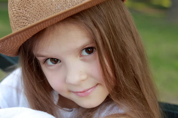 Adorable petite fille avec un chapeau posant à la caméra dans le parc d'été en plein air — Photo