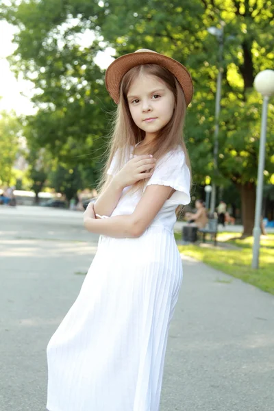 Caucasian smiling girl in a white dress and a hat outdoors — Zdjęcie stockowe