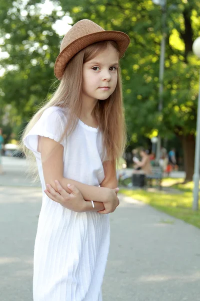 Glad liten tjej i en vacker hatt utomhus — Stockfoto