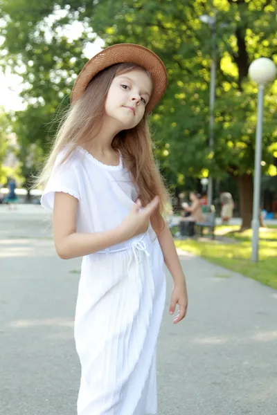 Caucasian smiling girl in a white dress and a hat outdoors — Zdjęcie stockowe