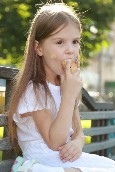 Little girl in a white dress is white ice cream outdoors — Stock Photo, Image