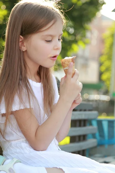 Enfant assis sur un banc mangeant de la crème glacée à l'extérieur — Photo