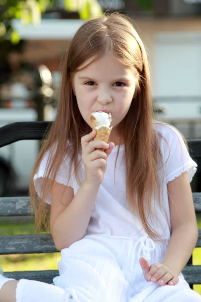 Kleines Mädchen im weißen Kleid ist weißes Eis im Freien — Stockfoto