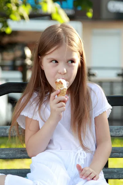 Dítě sedí na lavičce venku jíst zmrzlinu — Stock fotografie