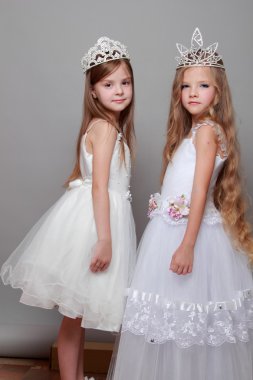 Beyaz giyinmiş ve moda ve güzellik üzerine bir taç giyen büyüleyici ve zarif küçük kızlar