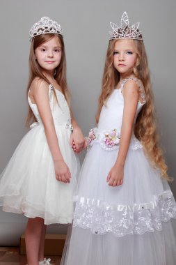 beyaz elbiseler ve bir taç gri bir arka plan üzerinde iki Avrupa kızlar