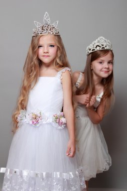 Beyaz giyinmiş ve moda ve güzellik üzerine bir taç giyen büyüleyici ve zarif küçük kızlar