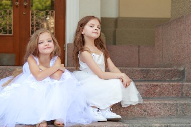 portre sevimli gülümseyen kız güzel bir elbise, uzun saçlı, açık havada basamaklarında oturan