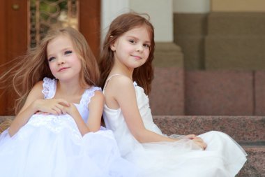 portre sevimli gülümseyen kız güzel bir elbise, uzun saçlı, açık havada basamaklarında oturan