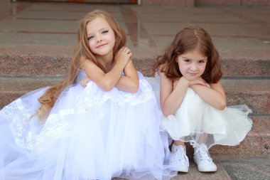 uzun beyaz elbiseler basamaklarında oturan uzun saçlı mutlu sevimli küçük kız