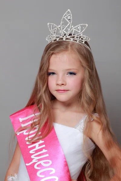 Bella bambina con lunghi capelli biondi in un abito da principessa bianco con un nastro rosso e la parola "Principessa del paese" sulla lingua ucraina — Foto Stock