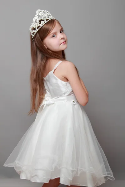 Belle petite fille en robe princesse aux cheveux longs sur fond gris — Photo