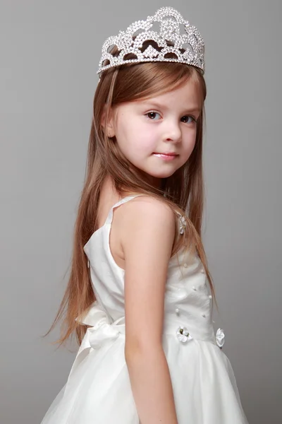 Европейская симпатичная молодая девушка в короне и белом платье с милой улыбкой на празднике — стоковое фото