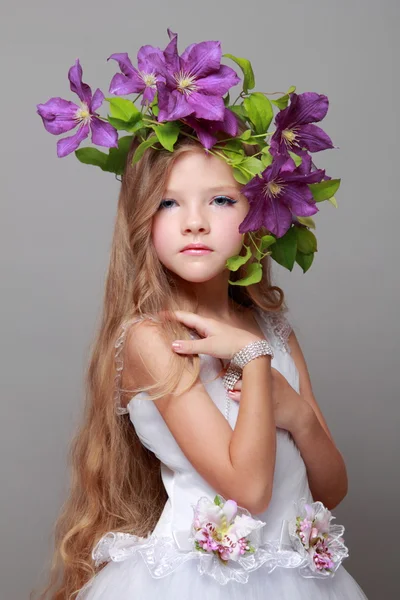 Caucasico carino bambina con bella acconciatura con fresco brillante clematide sorride e posa per la fotocamera — Foto Stock