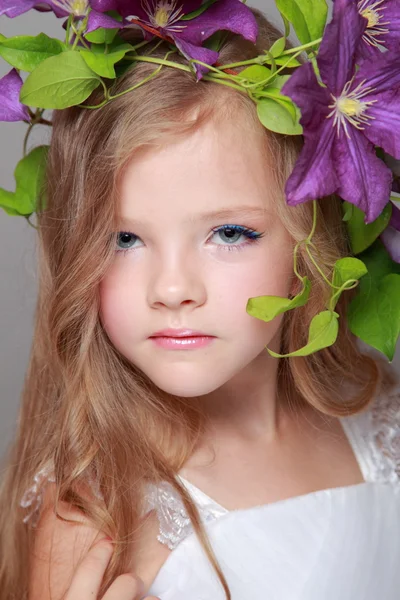 Šťastný roztomilá holčička s roztomilou účes fialové clematis, usmíval se na kameru na šedém pozadí — Stock fotografie