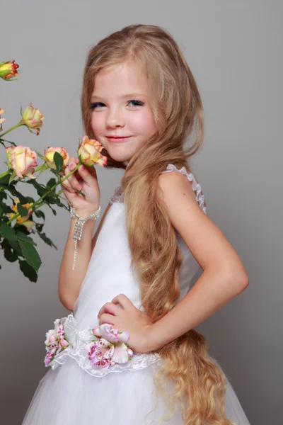 Studio image of a beautiful little girl with long blond hair near the fresh roses on Beauty and Fashion — Stock Photo, Image