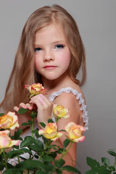 Imagen de estudio de una hermosa niña con el pelo largo y rubio cerca de las rosas frescas en Beauty and Fashion — Foto de Stock