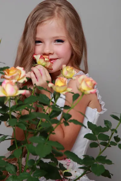 Image Studio krásná holčička má dlouhé blond vlasy poblíž čerstvé růže, krása a móda — Stock fotografie