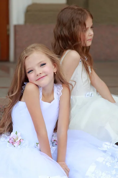 Deux jeunes filles en robes de mariée blanches assises sur les marches à l'extérieur du bâtiment — Photo