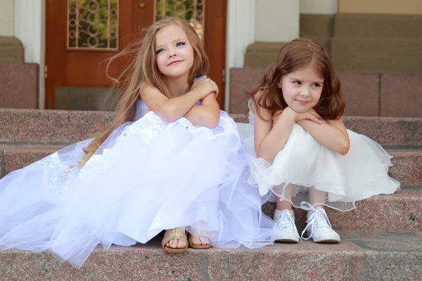 beyaz gelinlik içinde iki genç kız elbiseleri bina açık havada dışarıda basamaklarda oturup