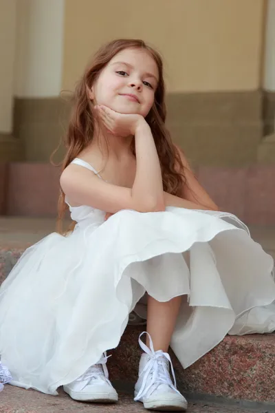 Charmantes junges Mädchen mit langen gesunden Haaren in einem schönen weißen Kleid, das draußen spaziert — Stockfoto