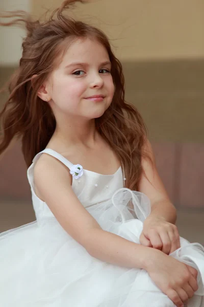 Charmig ung flicka med långt och friskt hår i en vacker vit klänning promenader utomhus — Stockfoto