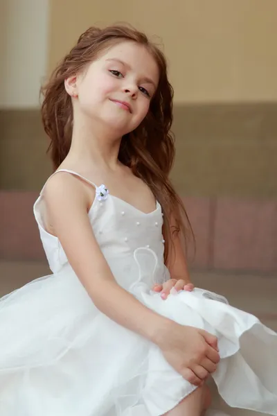 Retrato de linda niña sonriente con el pelo largo en un hermoso vestido está sentado en los pasos al aire libre —  Fotos de Stock