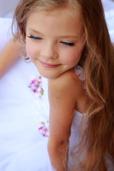 Elegant cute little girl with makeup in a white dress with beautiful hair — Stock Photo, Image