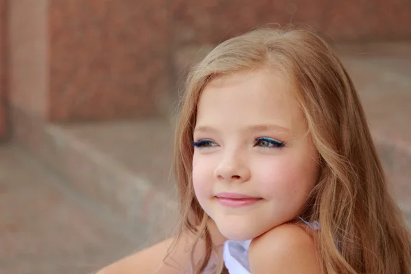 Boldog mosolygó kislány fehér golyó ruhát, és ült a lépcsőn szabadban — Stock Fotó