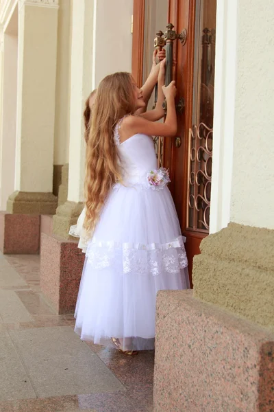 Dwa urocze dziewczynki w długą białą Suknie stanąć w pobliżu lustrzane drzwi na zewnątrz budynku — Zdjęcie stockowe