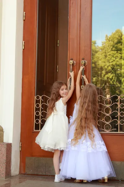 Genç kız beyaz gelinlik içinde bina açık havada büyük kapılarını açmak için çalışıyoruz — Stok fotoğraf