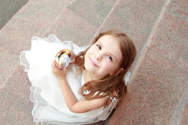 Feliz sorrindo menina em um vestido de baile branco e sentado nas escadas ao ar livre — Fotografia de Stock