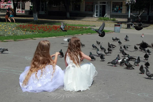 Glücklich fröhliches Mädchen in weißen Brautjungfer Brautkleider Füttern Tauben im Freien — Stockfoto