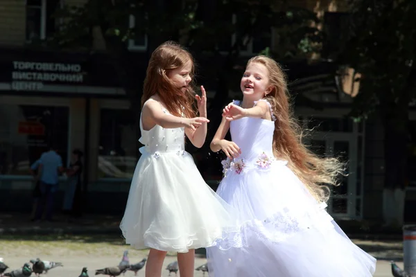 Vacker leende ung flicka med långt hår i långa vita klänningar mata duvor utomhus — Stockfoto