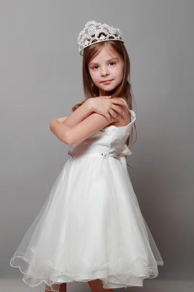 Vacker liten flicka i princess klänning med långt hår på grå bakgrund — Stockfoto