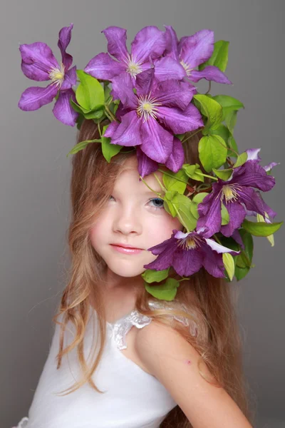 Cute little girl with beautiful hairstyle with fresh clematis — Stock Photo, Image