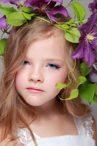 Schattig klein meisje met mooie kapsel met verse clematis — Stockfoto