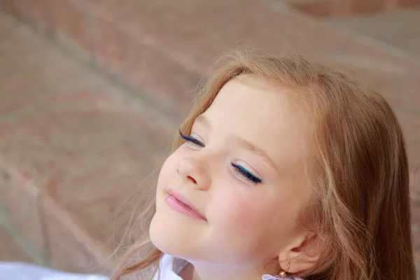 Retrato de linda niña sonriente con el pelo largo en un hermoso vestido está sentado en los pasos al aire libre —  Fotos de Stock