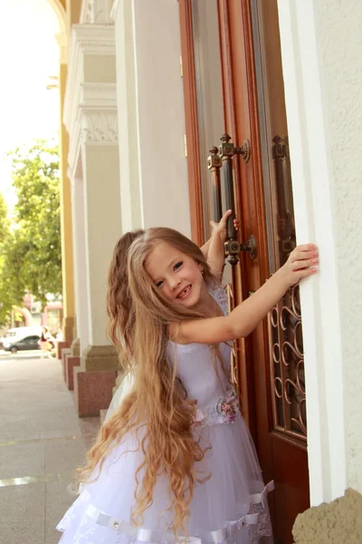 Young girl in white wedding dresses are trying to open the big doors to the building outdoors — Stock Photo, Image