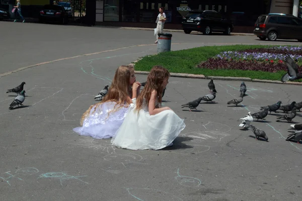 Dos niñas en vestidos de bola blanca alimentar palomas al aire libre — Stockfoto