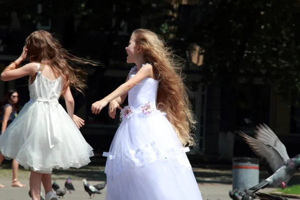 Dos niñas en vestidos de bola blanca alimentar palomas al aire libre — Stockfoto