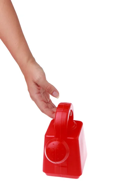 Female hand holding a small red watering can on a white background — Stock Photo, Image