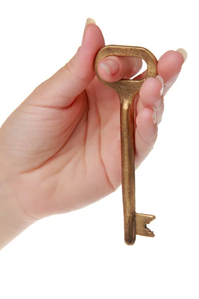 Mano femminile con una vecchia chiave in metallo su sfondo bianco — Foto Stock