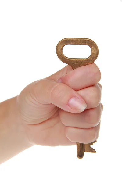 Bella mano donna con una vecchia chiave su uno sfondo bianco isolato — Foto Stock