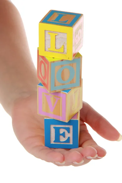 Adults hands hold children's blocks with the word love on a white background — Stock Photo, Image