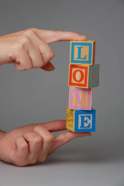 Frauenhände halten Kinderblöcke mit dem Wort Liebe — Stockfoto